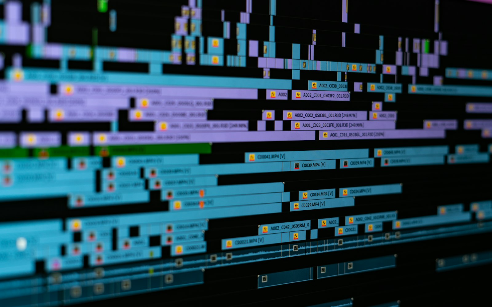 Angled close-up of a video editing timeline crowded with stacked blue and purple clips, many marked with small effects badges