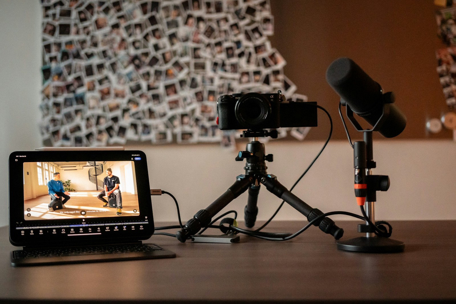 A creator’s desk set up to film a software review: a mirrorless camera on a small tripod, a microphone on a stand, and a tablet showing a video-editing timeline